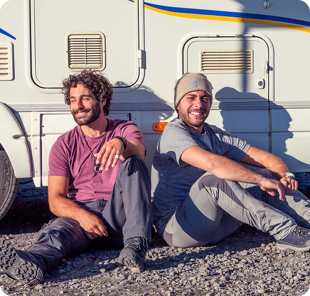 Two men sitting in the sun beside a camper van