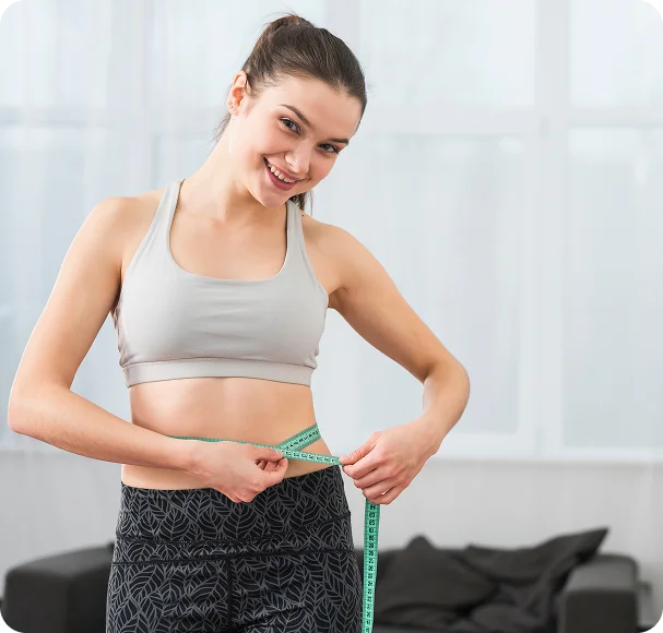 A woman in athletic wear measuring her waist with a tape measure