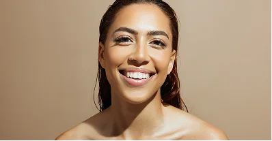 A smiling woman with glowing skin against a warm background
